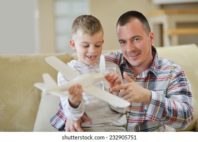 Vater und Sohn, die Flugzeugspielzeug in einem modernen Wohnzimmer zusammenbauen