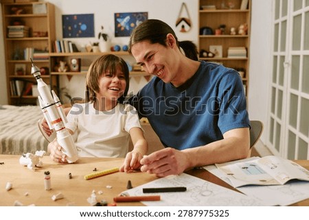 Father and son assembling toy rocket, learning through play and sharing bonding time at home. Concept of parenting, STEM education, family connection for parenting or learning campaigns
