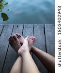 Father and son bare foots laydown together on a wooden board near the pond, love and tenderness 