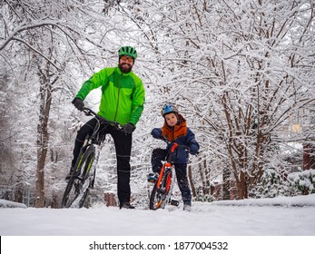 Father And Son With Bicycles In A Winter Park. Father Explains How To Ride A Bike. Weekend In The Winter Park