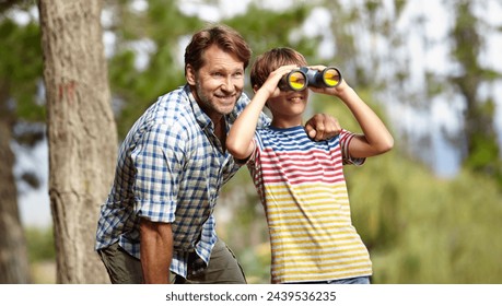 Father, son and binoculars in forest for outdoor adventure, birdwatching or learning by trees with smile. Dad, child and hug for vision, view and search for connection, care and bonding in woods - Powered by Shutterstock