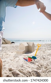 Father And Son Building Sandcastle Shaped Like House