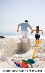 Father and son building sandcastle shaped like house