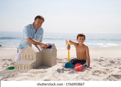 Father And Son Building Sandcastle Shaped Like House