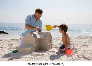 Father And Son Building Sandcastle Shaped Like House