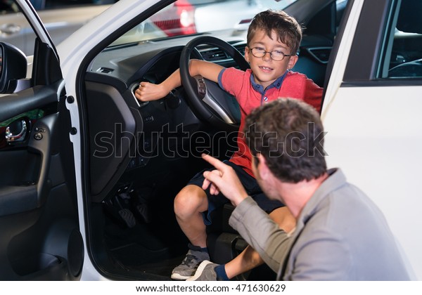 Father\
and son buying new family car at auto\
dealership