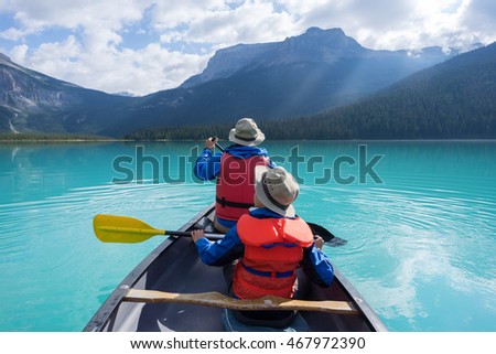 father and son canoeing on Emerald lake early morning with sun rays spilling over the mountains
