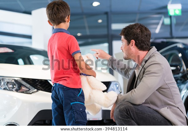 Father with\
son in car dealer showroom buying\
auto