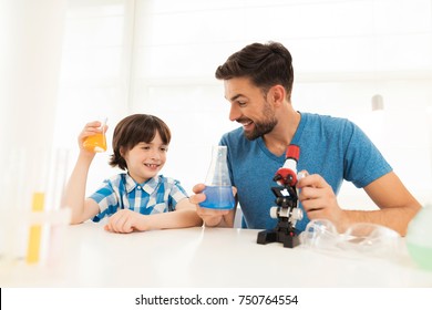 Father and son conduct chemical experiments at home. They use a microscope, flasks, chemical liquids. This is homework to school. - Powered by Shutterstock