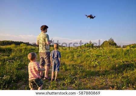 Father and son controls RC drone quadrocopter in the sky