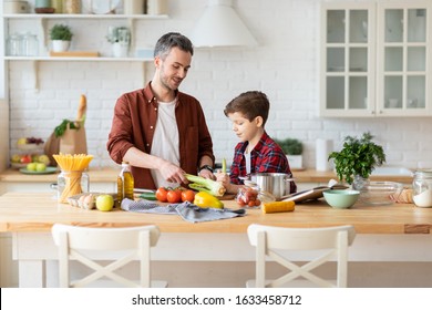 Father son cooking fresh vegetables on kitchen. Dad and boy child break down celery stalk. Healthy salad preparation. Raw ingredients on table. Family communicating, culinary and enjoying weekend time - Powered by Shutterstock