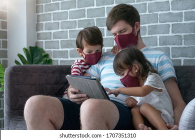 Père avec son fils et sa fille portant des masques de visage, couvrant leur visage pendant la pandémie mondiale de coronavirus-19, utilisez un Tablet PC pour regarder les informations dans le salon à la maison