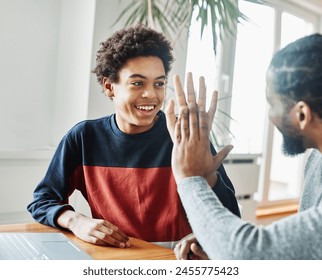 Father and son doing homework with laptop at home. Father and teenage son using laptop. Father and son giving high five hand to each other. Teamwork and cooperation concept - Powered by Shutterstock