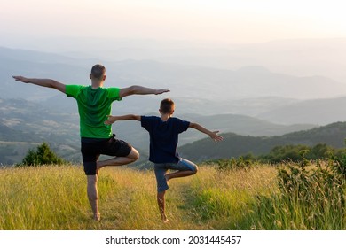 Father and son doing yoga Tree pose at top of mountain. Family stretching after sport. Sport healthcare together. Healthy habits. Family doing yoga outside in bright sunny day, lovely emotions - Powered by Shutterstock