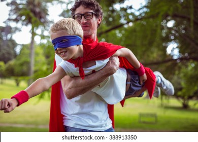 Father And Son Dressed As Superman In The Garden