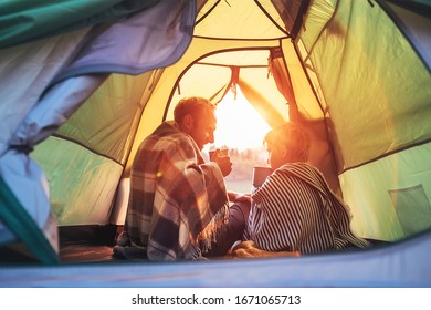 Father and son drink hot tea sitting together in camping tent. Traveling with kids and active people concept image. - Powered by Shutterstock