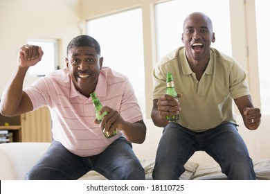 Father And Son Drinking Beer And Cheering At Television