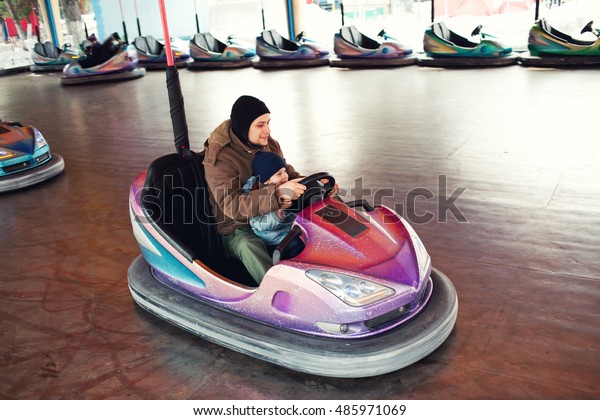 Father\
and son driving bumper car in an amusement park\

