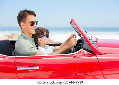 Father And Son Driving Convertible At Beach