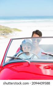 Father And Son Driving Convertible On Beach