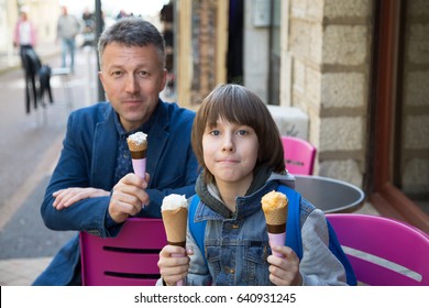 Father And Son Eating Ice-cream In Street Cafe, Family Lifestyle. Dad With Offspring Enjoying Icecream Spring Outdoor