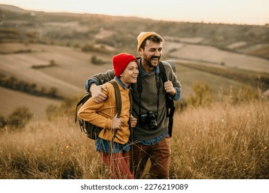 Father and son embraced walking in a grass field during the nature sunset.