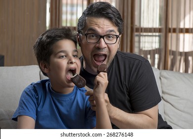 Father and son enjoying chocolate-coated blocks of ice cream on stick. - Powered by Shutterstock