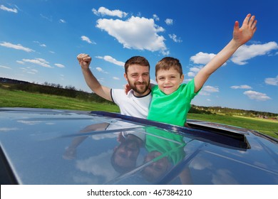 Father And Son Enjoying Freedom On Sunroof Of Car