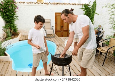 Father and son enjoying quality time together by the poolside roasting marshmallows on a grill. Family bonding and summer outdoor fun. - Powered by Shutterstock