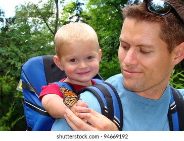 Father and son exploring nature - boy smiling with a butterfly on his hand