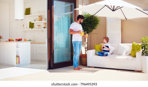 Father And Son, Family Relaxing On Rooftop Patio With Open Space Kitchen At Warm Summer Day