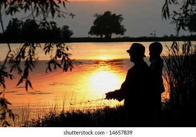 Father And Son Fishing At Dusk.