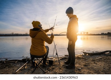 Father and son are fishing on winter day. River fishing. Teenage boy is learning to fish. - Powered by Shutterstock