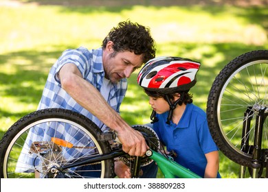 Father And Son Fixing The Bike In A Park