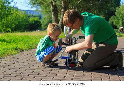 Father And Son Fixing Bike In Summer Park