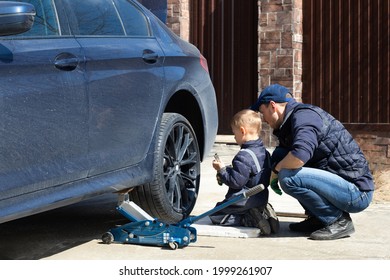 Father and son are fixing the car. The son helps the dad. Happy Father's Day. 