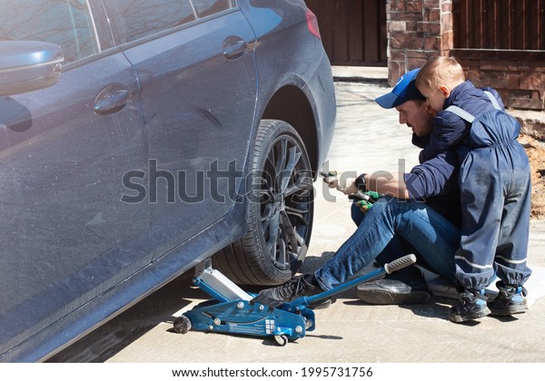 Father and son are fixing the car. The son helps\
the dad. Happy Father\'s Day.\
