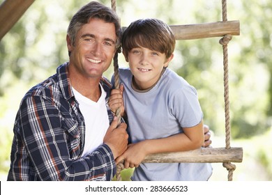 Father And Son In Garden By Treehouse