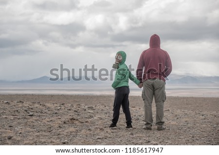 father and son in a gas mask in the desert steppe. Apocalypse postnuclear Doomsday scenario.