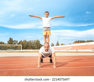 Father And Son Go In For Sports Together At The Stadium On Sunny Day. Selective Focus