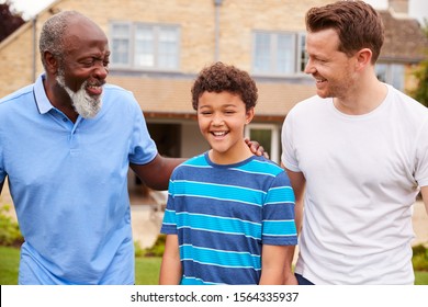 Father With Son And Grandfather From Multi-Generation Mixed Race Family Walking In Garden At Home