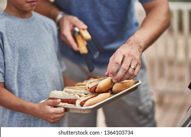 Father And Son Grilling Hot Dogs Together On Backyard Gas Grill