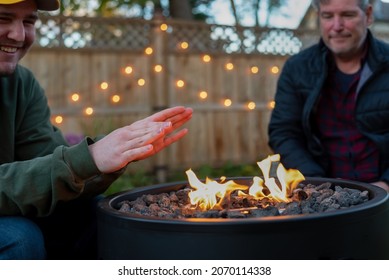 Father And Son Hanging Out In The Backyard By A Fire