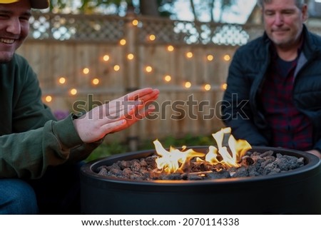 Father and son hanging out in the backyard by a fire