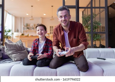 Father and son have fun playing in the console on the sofa - Powered by Shutterstock