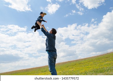 Father And Son Having Fun Outdoors. Father Throwing Young Boy Up Into The Air. 