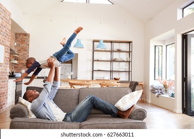 Father And Son Having Fun Playing On Sofa Together