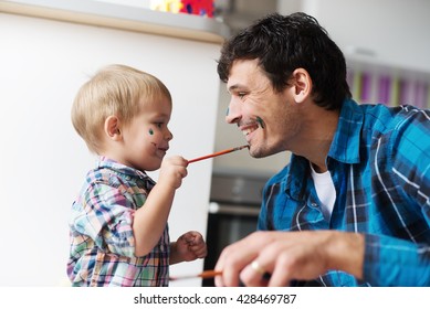 Father And Son Having A Good Time. Kid Is Painting Father's Face With Watercolors. Shallow Depth Of Field.