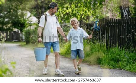 Father and son heading to Easter Monday visits with whip and water bucket.