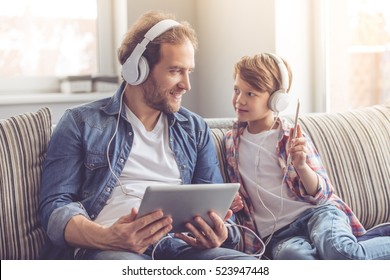 Father and son in headphones are listening to music using gadgets and smiling while spending time together at home - Powered by Shutterstock